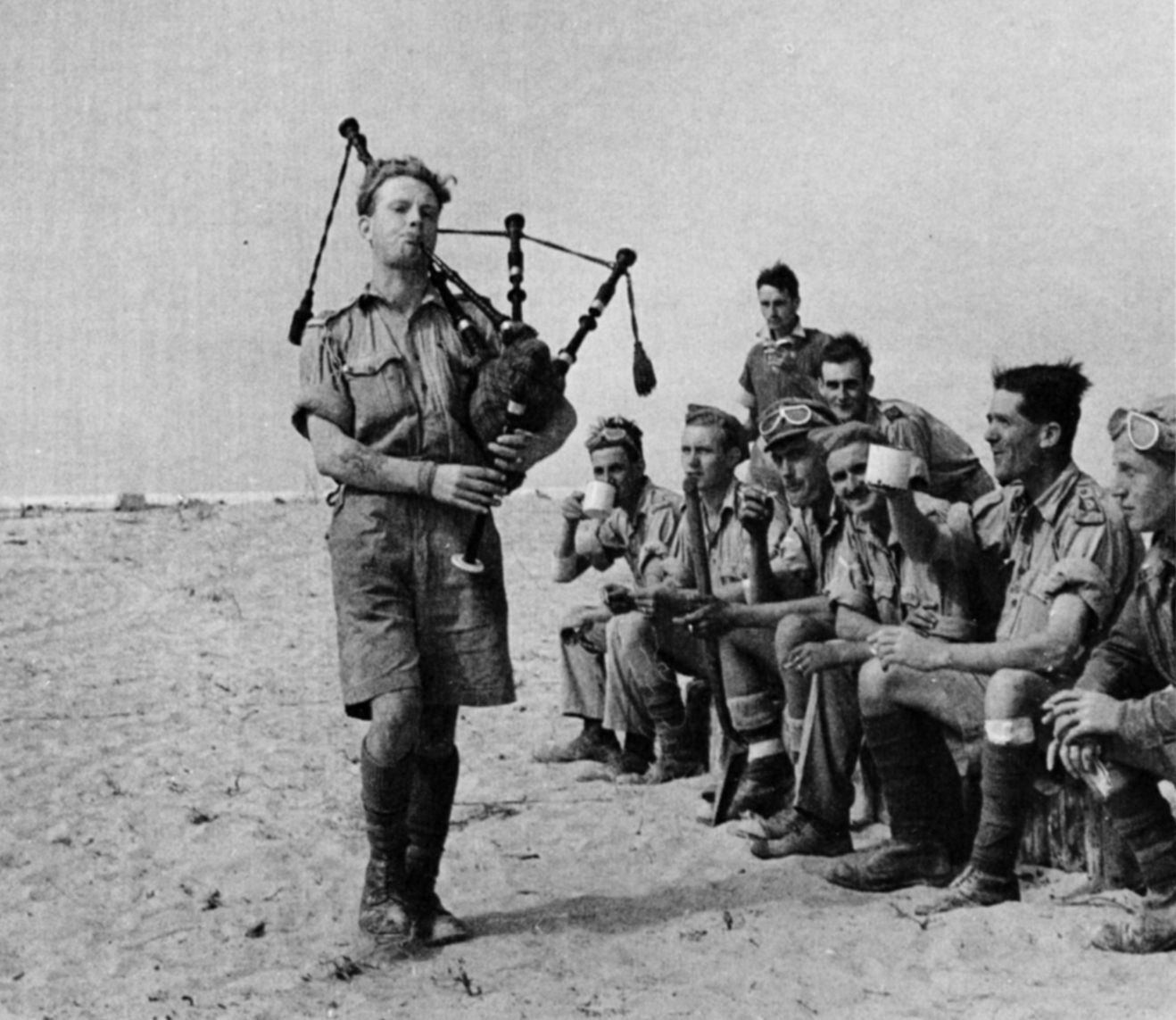 在沙漠中战斗间歇,即兴音乐会的风笛手娱乐英国士兵。