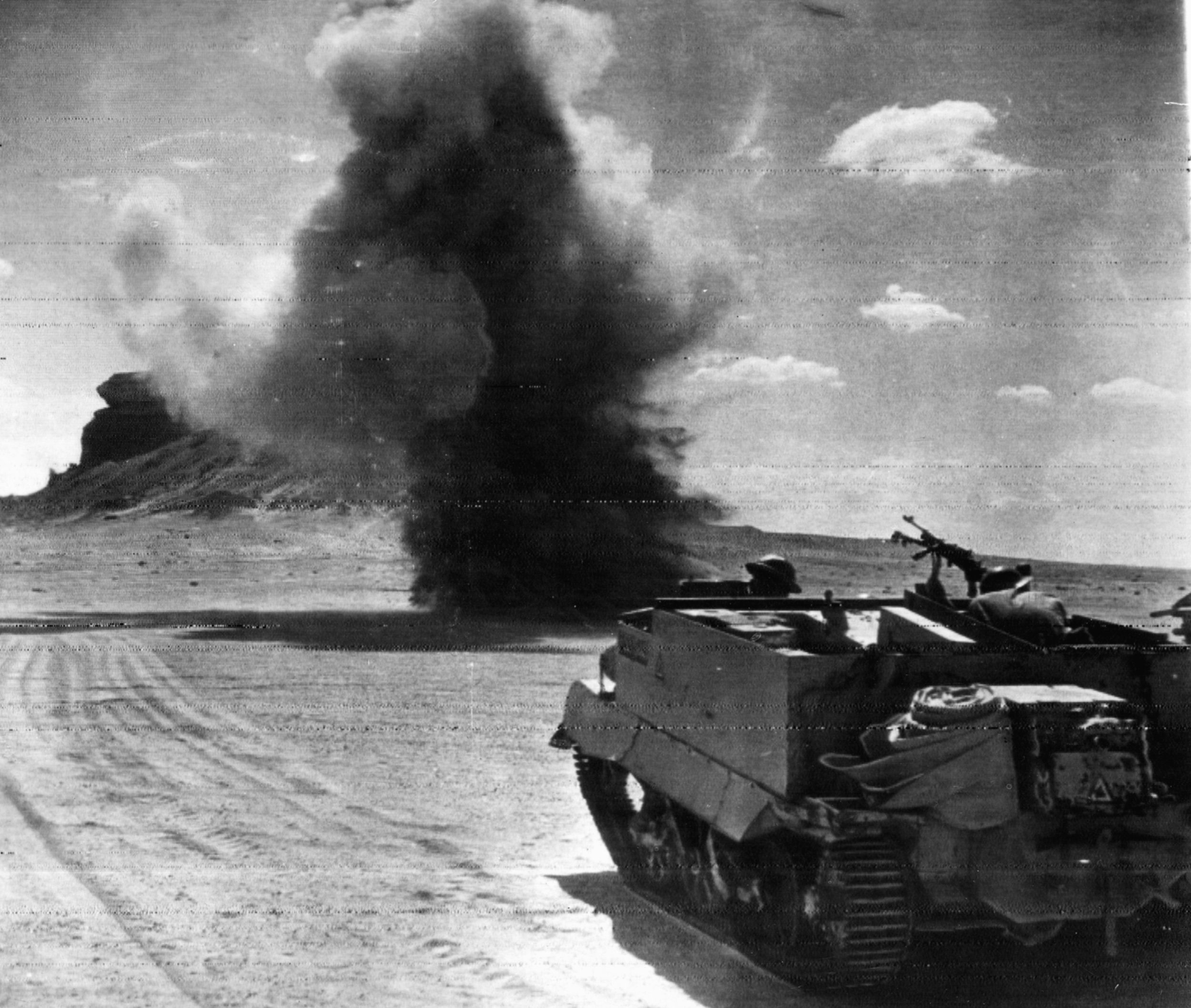 巡逻在布朗式轻机枪载波,一群英国士兵受到来自德国炮兵定位在沙漠的地平线。