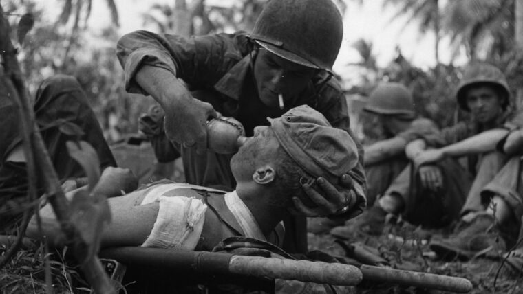 海军陆军医护兵给一杯水一个受伤的海洋关岛在太平洋岛上的。除了成千上万的人员伤亡被美国军队医务人员,美国海军也为战争训练了许多。(照片:国家档案馆)­