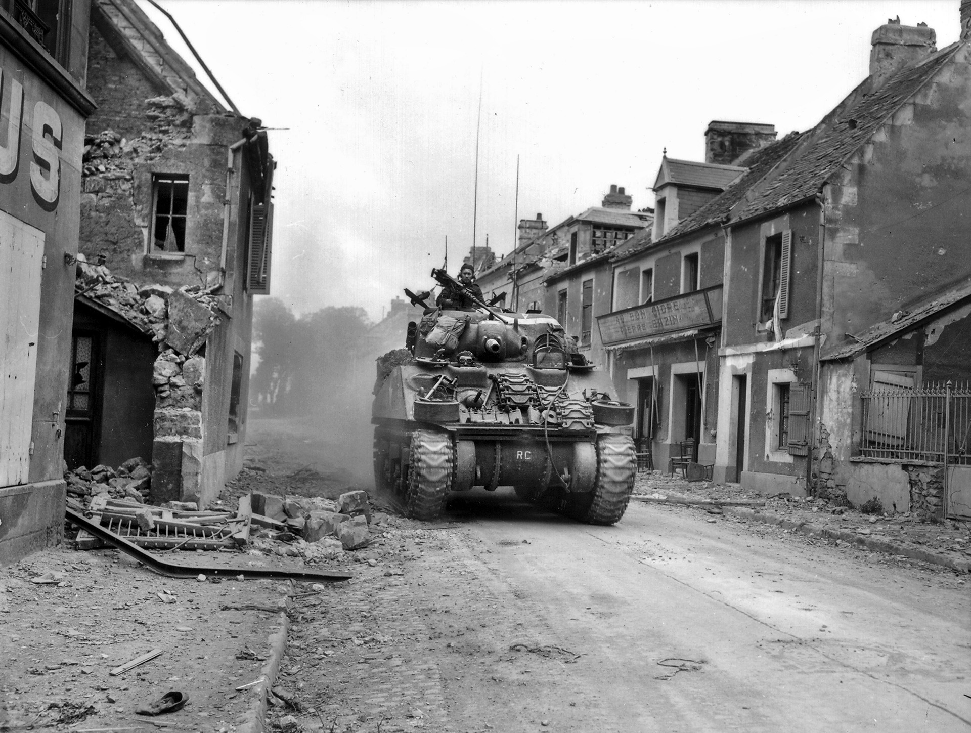 加拿大27日坦克军团的谢尔曼坦克通过破碎的卷,卡昂在德国退出空无一人的街道上。英国/加拿大人失去了成千上万的男人和300 - 500坦克。延迟在确保卡昂蒙哥马利严重受损的声誉之间的盟友。