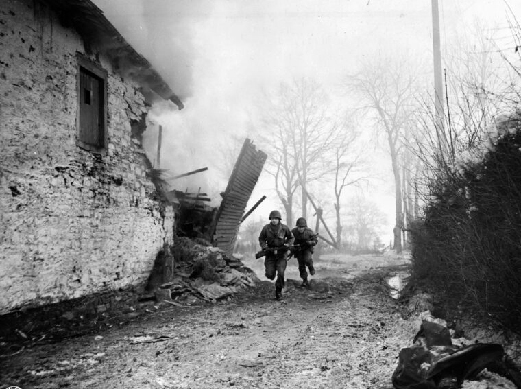 在突出部战役中，两名美国士兵正在寻找掩体。1944年12月，纳粹发动了阿登攻势，希望越过默兹河，推进到比利时的安特卫普港，将盟军部队分成两部分。希特勒在阿登攻势发动两周后授权北风行动，试图利用盟军在阿登威胁下转移部队和军事资产时在北方取得的战果。哈顿的阵地对于从德军手中夺取主动权至关重要。