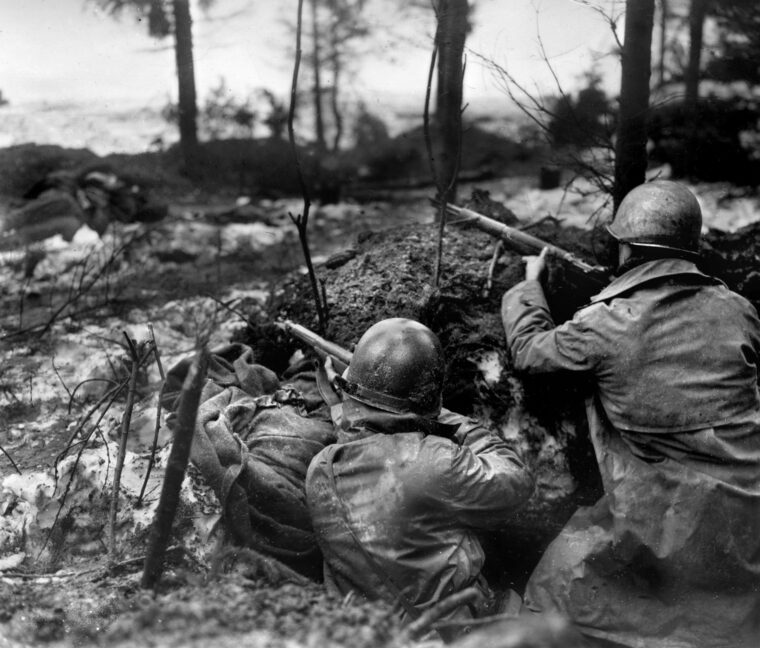 突出部战役期间，第99步兵师的两名美国士兵在用原木加固的散兵坑中观察和等待德军的进攻。20岁的布赫中尉和他指挥的21名士兵在兰泽拉斯的英勇坚守，延缓了佩佩尔战斗群的前进。