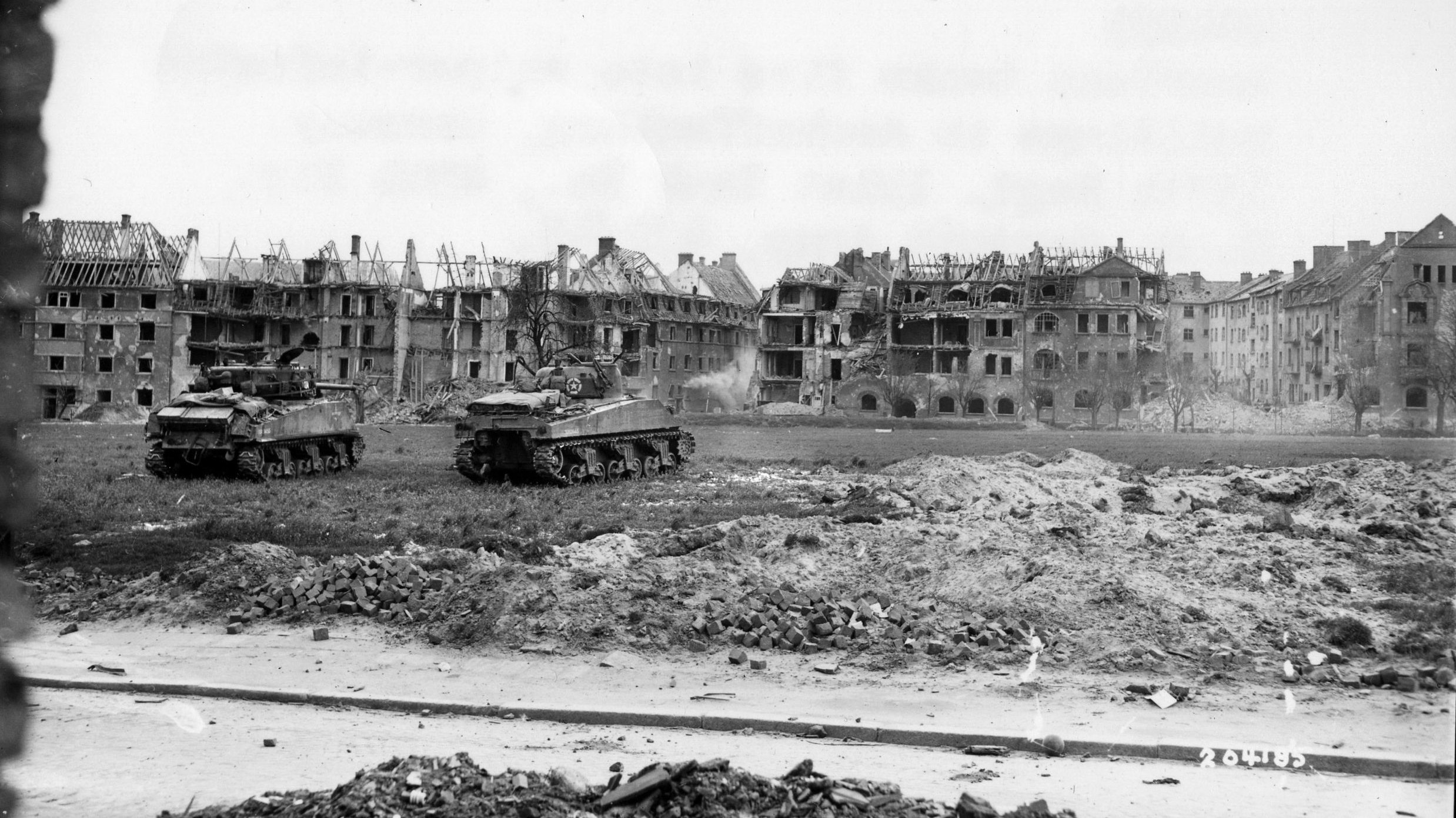 在阿沙芬堡，两辆谢尔曼坦克用重炮对准狙击阵地。德国狙击手有能力阻止无法离开掩体的美军大队形。